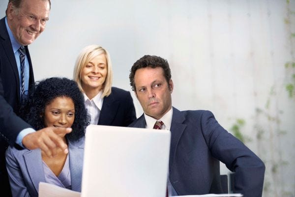 People in business clothes looking at a computer screen.