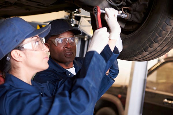 Photo Of A Student Learning Auto Mechanics Being Directed By Her Teacher