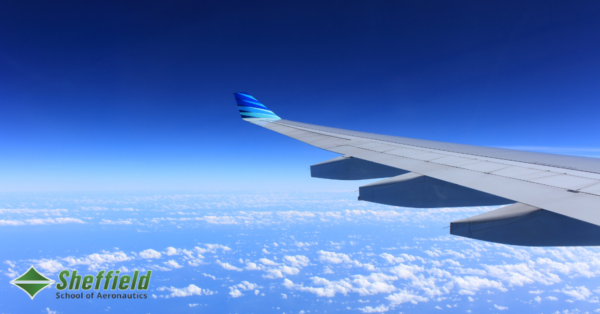 : A plane flying across a blue sky full of small white clouds.