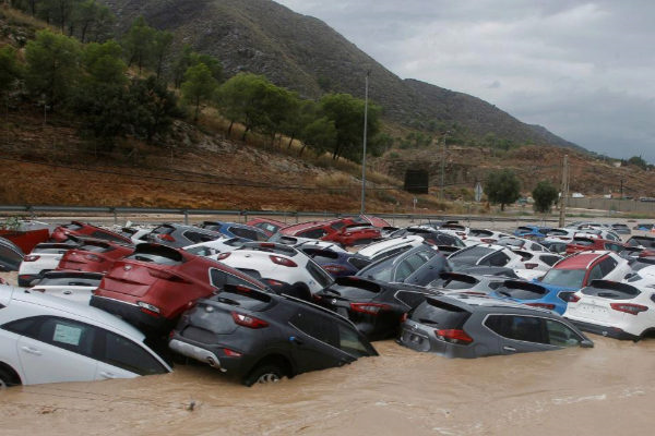 The image shows hundreds of cars pilled up covered with water due to the floods in 2019