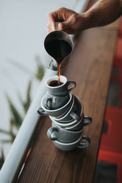 Tall stack of coffee cups balanced, with coffee poured in the top, to symbolize balance.
