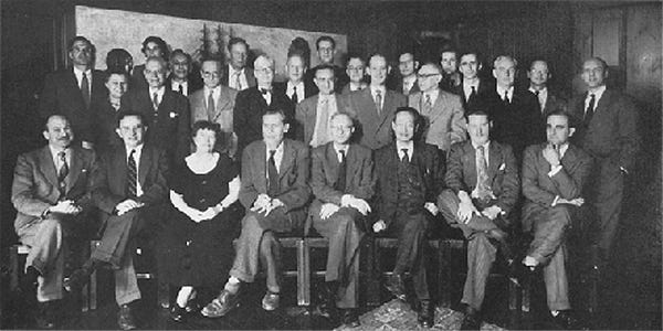 A large group of 20+ people in academic garb posing for a group photo in the late 1940’s. There are only a few women and all are Western.
