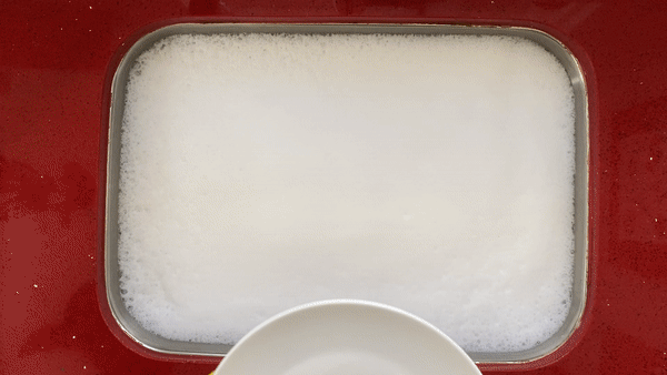 Person slowly dunks a white plate into even whiter soapy dish water.