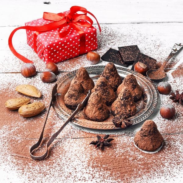 Chocolate Truffles in a dessert dish with tongs and a gift box wrapped in red polka dots.