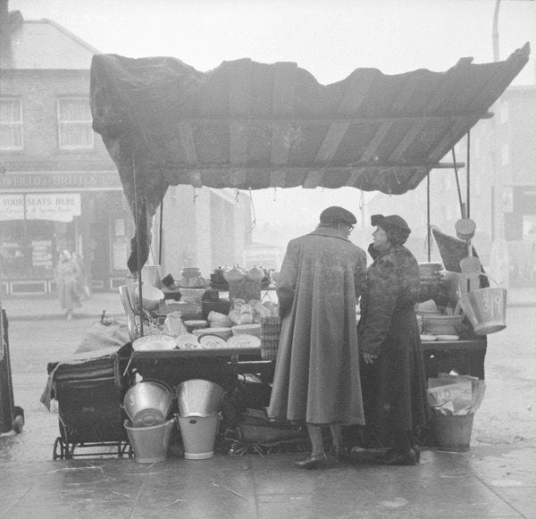 A couple buying kitchen appliances from a street vendor in London 1949
