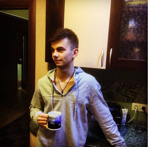 A young 17 years old boy stands with a mug in his hand