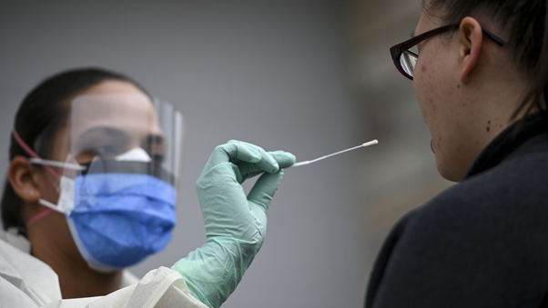 A doctor in protective gear swabs a patient