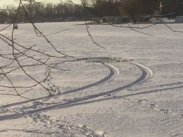 A frozen lake with tire tracks in the snow