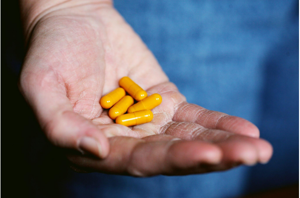 Six yellow pills in a person’s hand.