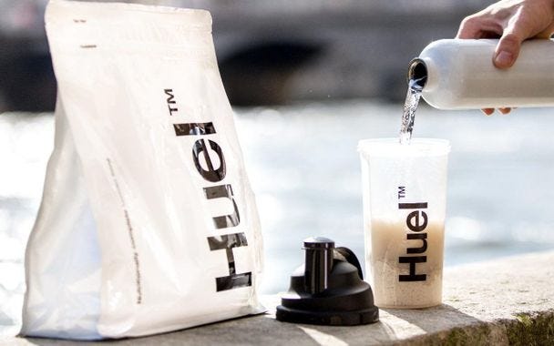 Glass of powder food, Huel, being mixed with water to drink