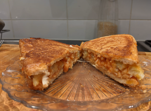 A toasted sandwich containing beans, cheese and hash browns.