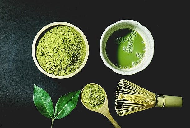 Matcha tea layout with leaf, powder and traditional whisk.