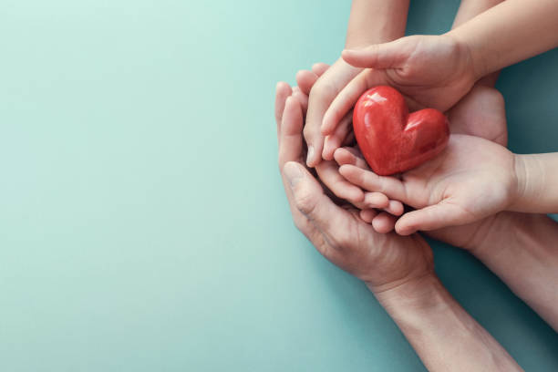 Multiple hands holding a small red heart