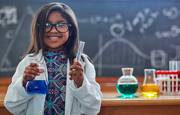 A girl wearing a lab coat and holding chemical tubes