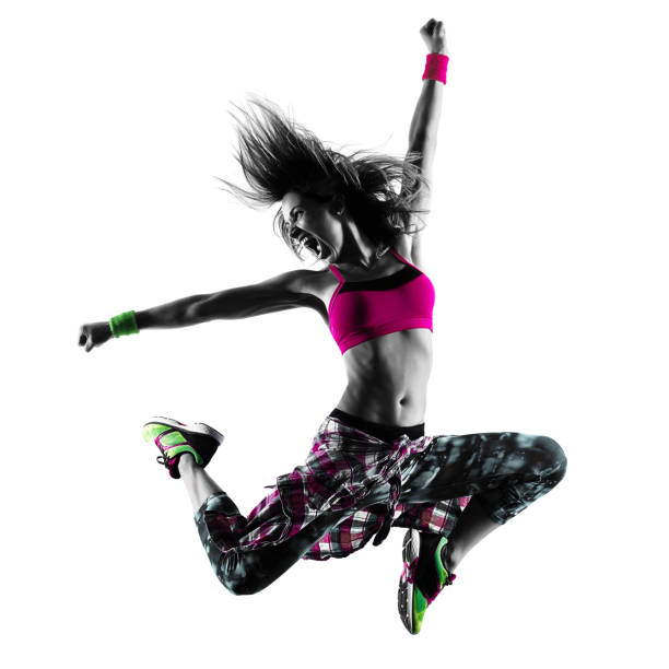 A woman wearing a pink top and joggers jumping in the air