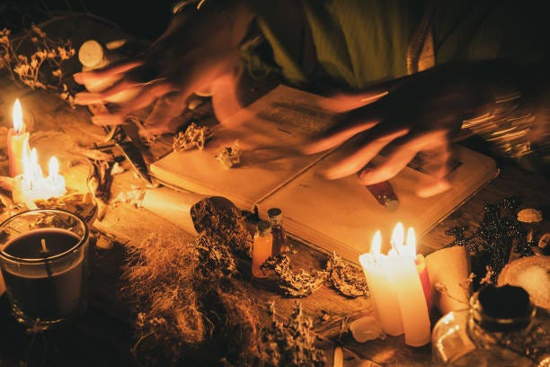 Hands fortune teller over an ancient table with herbs, books and candles. Manifestation of occultism in the form of divination.