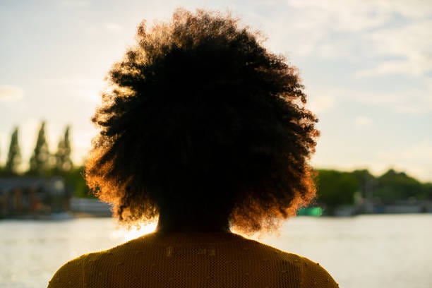 A black woman dreaming with her eyes opened looking at the sky.