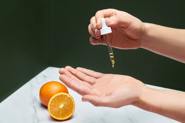 Vitamin C serum pouring from droplet on hands for massaging