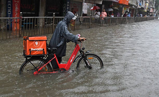 A Swiggy rider navigating a flooded street — the disruption EarnSafe protects against.