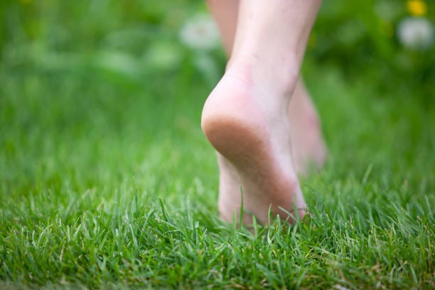 A person walking barefoot on grass