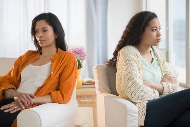 Two women who are sitting with their backs against each other due their anger.