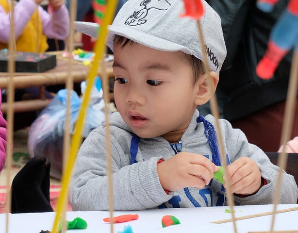 toddler boy at colorful table with play-doh and sensory toys