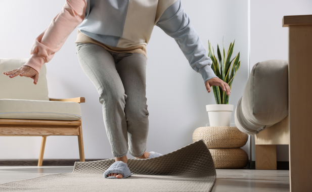 A person stumbling and regaining their balance from their feet catching on a rug.