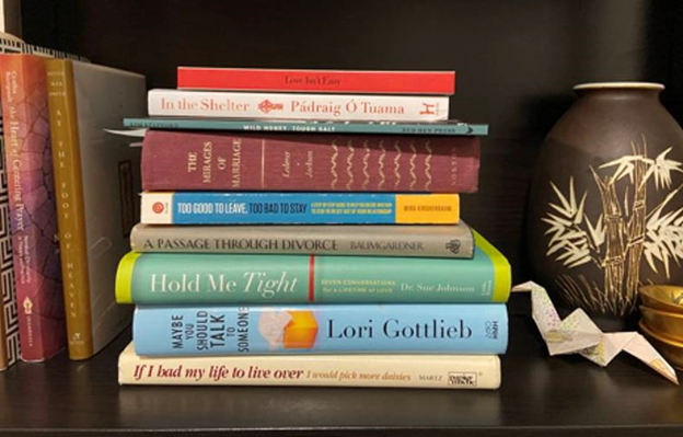 Books on love, marriage, and poetry on a shelf with an origami peace crane