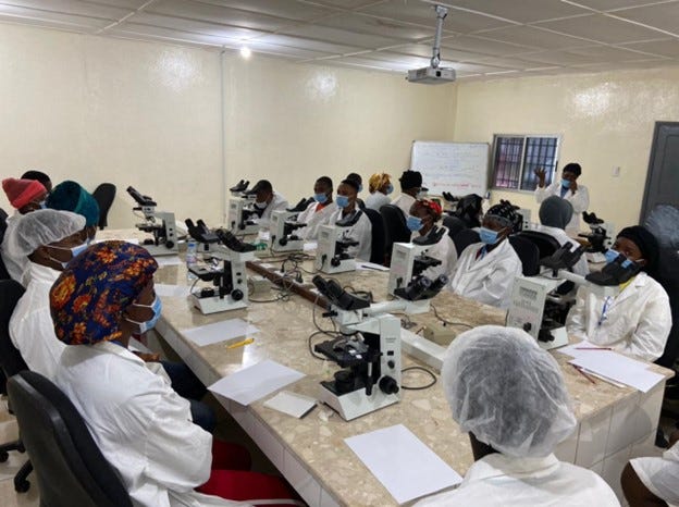 A group of people sitting around a table that holds several pieces of scientific equipment.