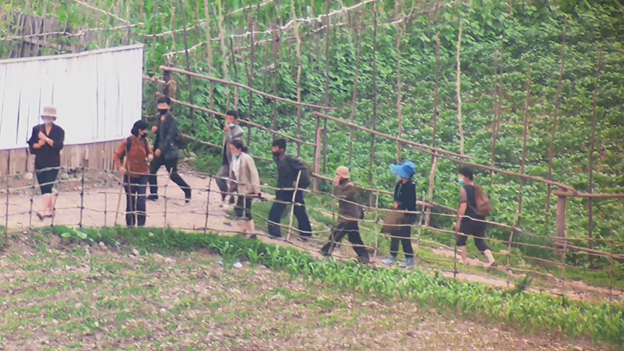 North Koreans walking between farm fields
