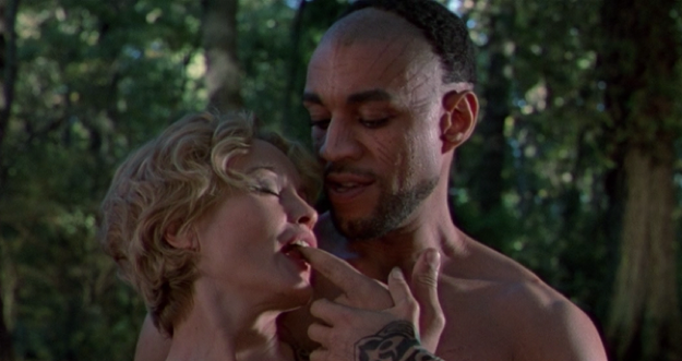 A naked woman leans into a naked man’s chest. The man places the woman’s finger in her mouth.