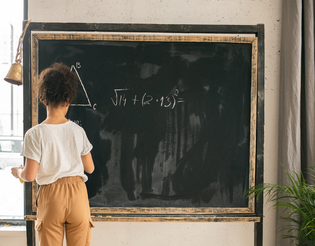 Unrecognizable girl solving mathematical problems near chalkboard · Free Stock Photo