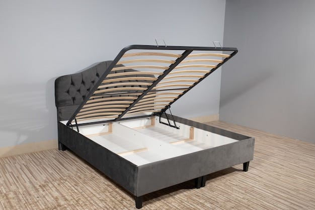 bed with gray upholstery, without mattress and with opened storage in an empty room