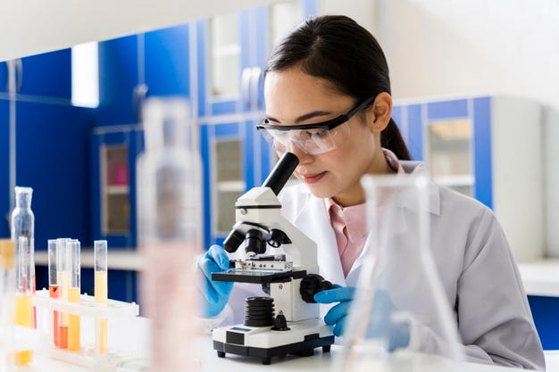 A woman looking into a microscope in lab