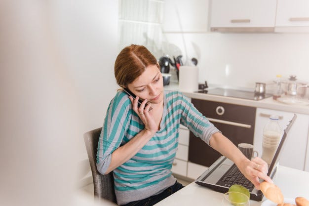 A woman picking up a cookie while working