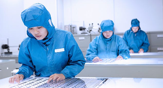 Researchers wearing blue protective garments working in a laboratory.