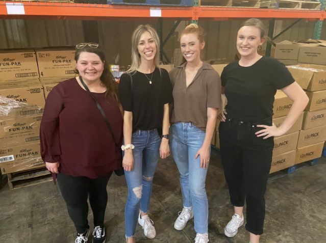 Team members stand in a line in front of a warehouse of boxes