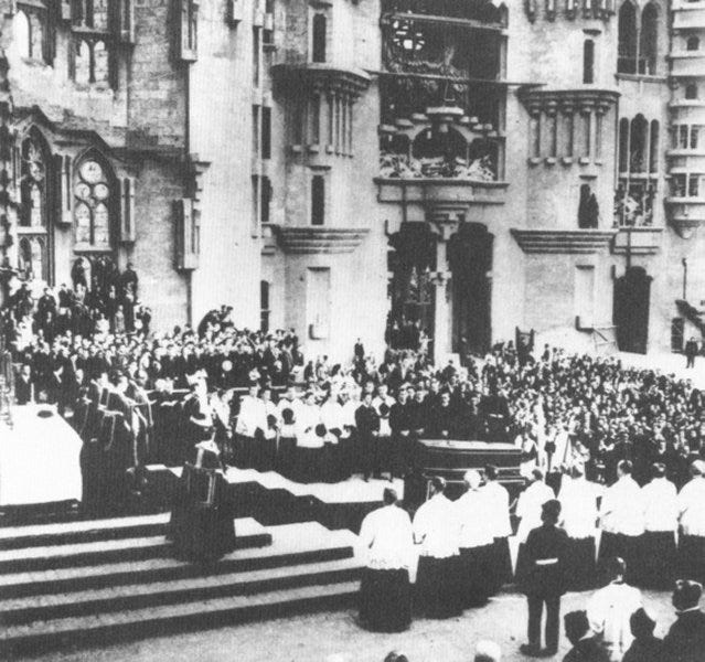 A grainy black and white photo of a crowded funeral procession.