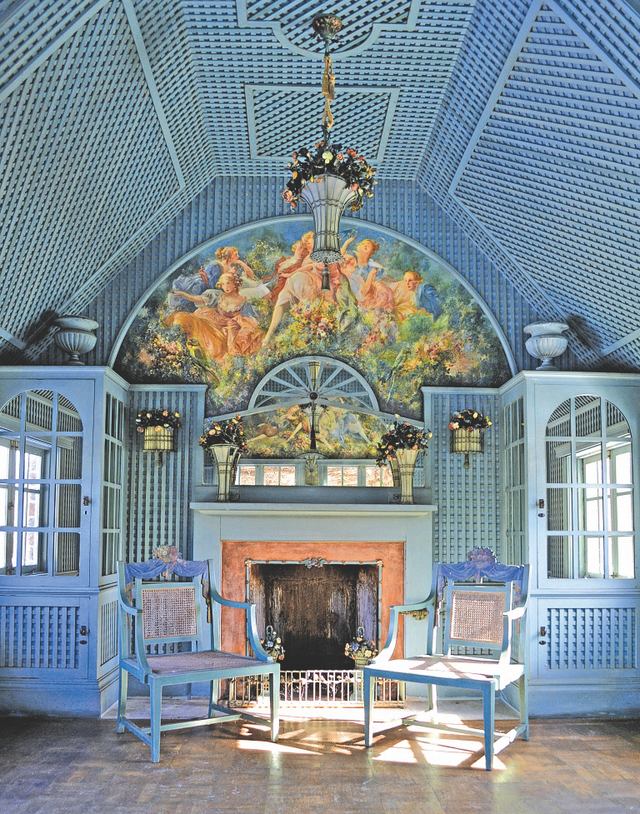 Pale blue tea room by Elsie De Wolfe. Features a Rococo painting, orange lined fireplace, garden trellis panels and high ceilings.