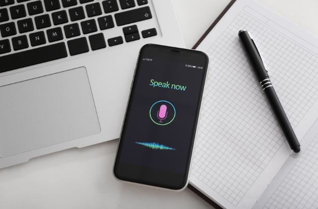 smart phone on a table with the text ‘speak now’ and an icon of a microphone on the screen