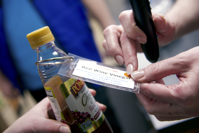 Debra uses her hands and a talking label-reader device to determine what’s in a bottle