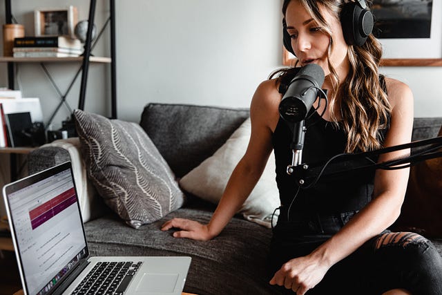 A woman talking to a microphone to record her podcast