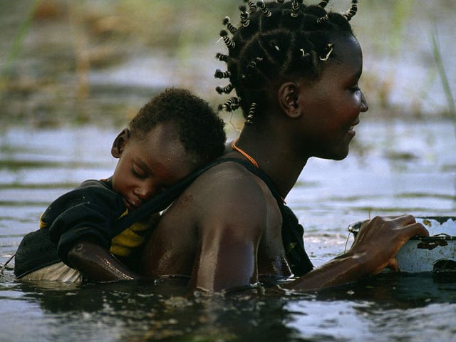 A Mbukushu mother and child cross Botswana's Okavango River, whose seasonal floods bring life to a parched land.   From the National Geographic book Mothers and Children, 2009