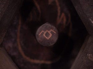 The Owl Cave symbol appears on the bottom of a cylindrical stone. 