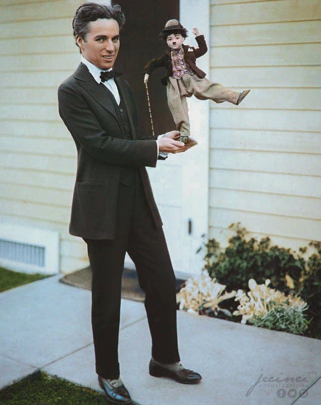 Charlie Chaplin holding a puppet version of his character, “The Tramp”