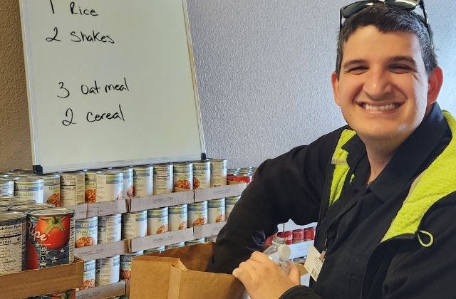 man packing canned food into a brown paper bag