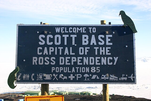 A sign saying “Welcome to Scott Base, Capital of the Ross Dependency. Population: 85”