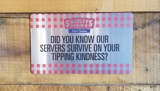 Sign on wall. Text reads: “Swadley’s BAR-B-Q, World Famous. Did you know our servers survive on your tipping kindness?”