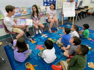 Three Marlton Middle School (MMS) seventh-graders, from left, Ethan Elwell, Amanda Elwell, and Alicia Phillps, read to three- and four-year-old children at Teddy Bear Academy (TBA), after presenting  the organization with books worth $200, raised from funds collected at MMS' fall and spring book fairs through the Scholastic All For Books Program. Scholastic matched all money raised and will donate books to kids in need as well.