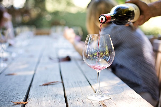 Pouring red wine outside at a wooden picnic table